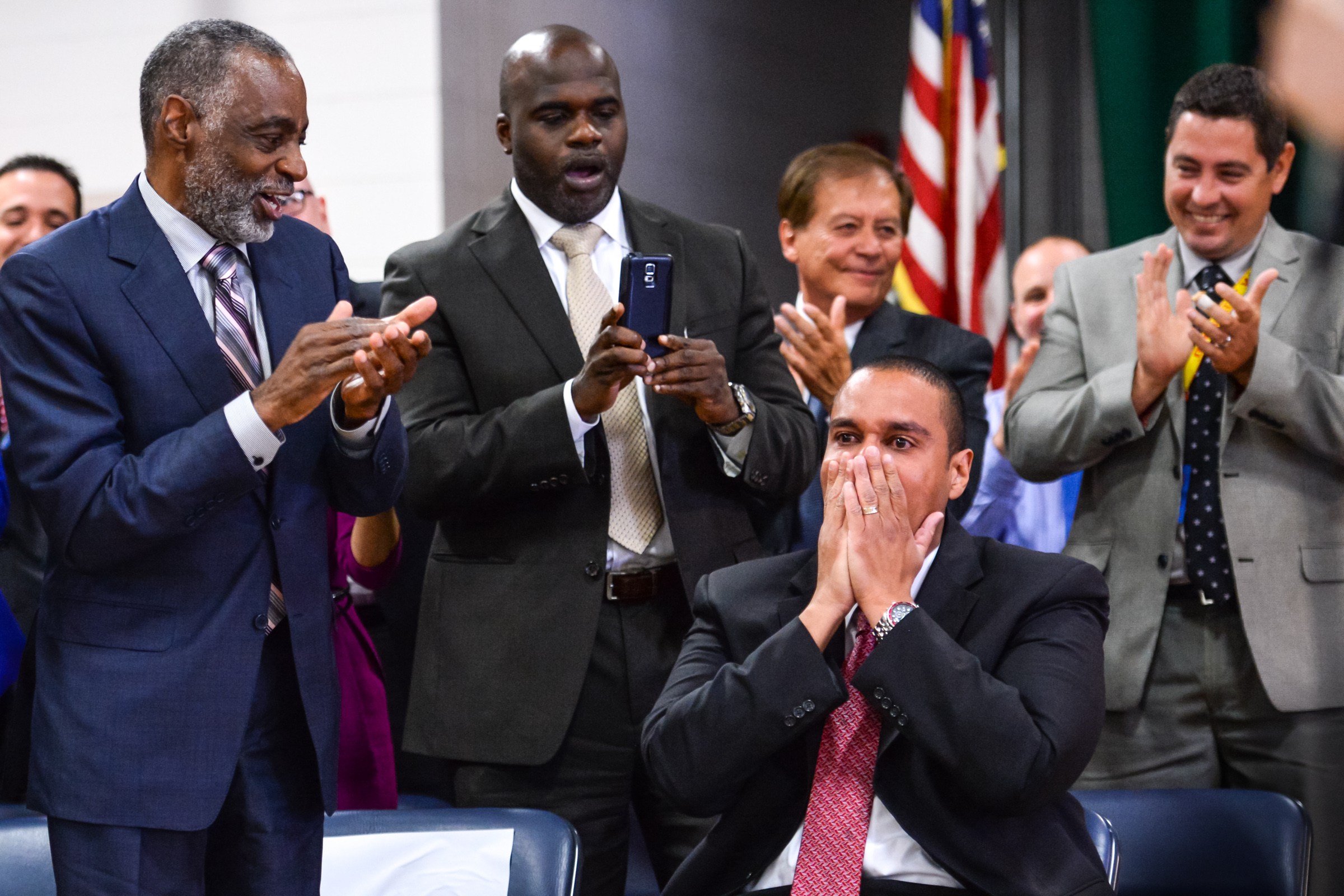 Desi Nesmith, seated, reacts to winning the Milken Educator Award.